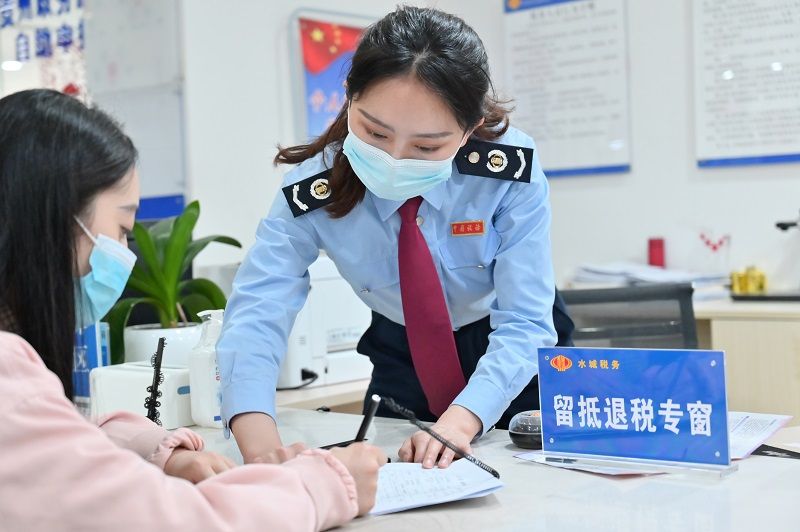 水城區(qū)稅務局窗口工作人員正在輔導納稅人填寫資料。（張定國攝）.jpg